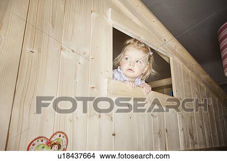 Picture - Girl peeking out window of playhouse. Fotosearch