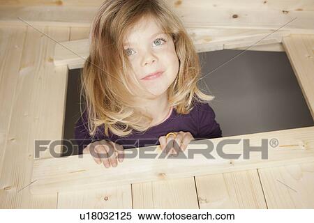 Stock Photography - Girl peeking out window of playhouse. Fotosearch