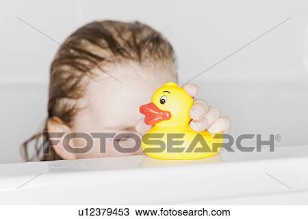 Stock Image - Girl playing with rubber duck in bath. Fotosearch