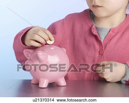 Girl putting coin in piggy bank View Large Photo Image Picture - Girl putting coin in piggy bank. Fotosearch