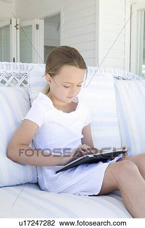 Girl using tablet computer on sofa View Large Photo Image Stock Image - Girl using tablet computer on sofa. Fotosearch