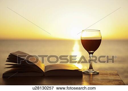 Stock Photo - Glass of wine and book on table outdoors. Fotosearch