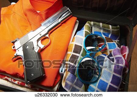 Stock Image - Gun and sunglasses in suitcase. Fotosearch