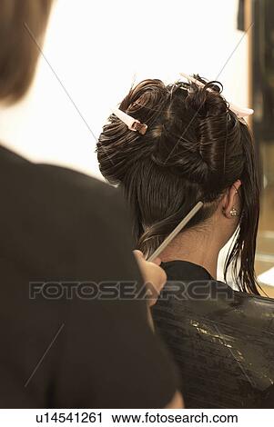 Stock Image - Hair stylist working on clients hair. Fotosearch