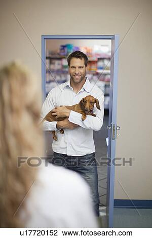 Stock Image - Man bringing dog to veterinarian. Fotosearch