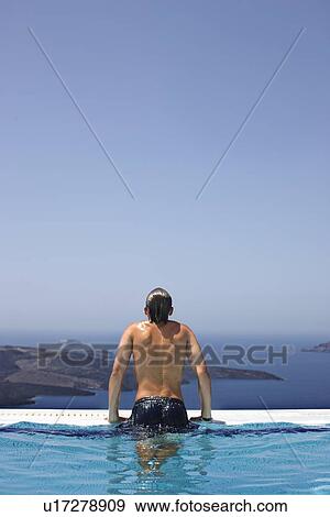 Stock Photo - Man climbing out of infinity pool. Fotosearch