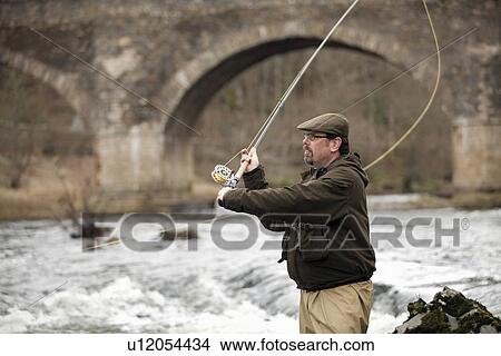 Picture - Man fishing for salmon in river. Fotosearch