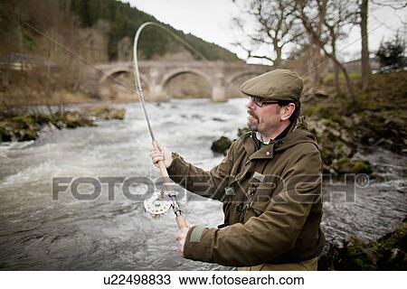 Stock Image - Man fishing for salmon in river. Fotosearch