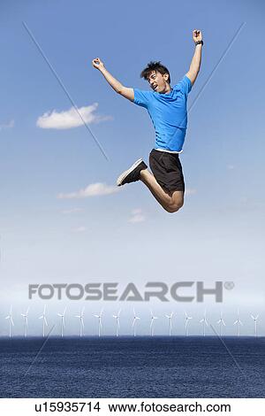 Man jumping for joy over wind turbines View Large Photo Image Picture - Man jumping for joy over wind turbines. Fotosearch