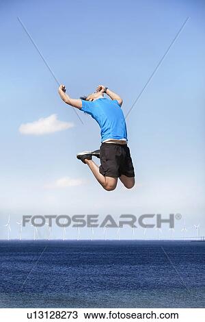 Man jumping for joy over wind turbines View Large Photo Image Stock Image - Man jumping for joy over wind turbines. Fotosearch