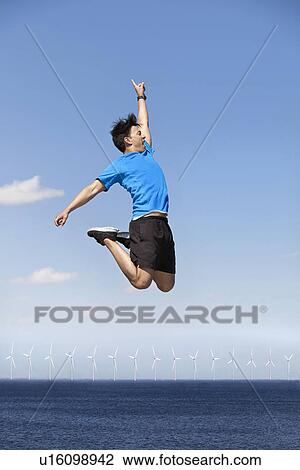 Man jumping for joy over wind turbines View Large Photo Image Stock Image - Man jumping for joy over wind turbines. Fotosearch
