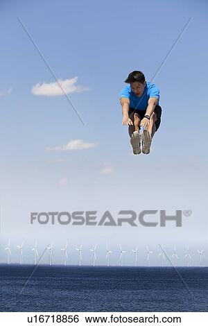 Man jumping for joy over wind turbines View Large Photo Image Stock Photograph - Man jumping for joy over wind turbines. Fotosearch