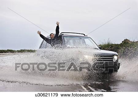Man leaning out of splashing car View Large Photo Image Stock Photo - Man leaning out of splashing car. Fotosearch