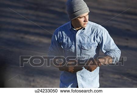 Stock Image - Man pulling off gloves outdoors. Fotosearch