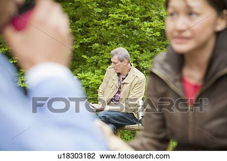 Stock Image - Man reading newspaper in park. Fotosearch
