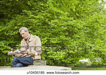 Stock Photography - Man reading newspaper in park. Fotosearch