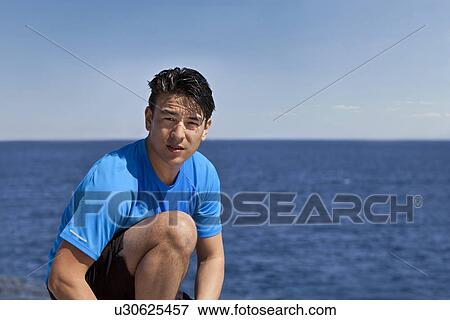 Man sitting on coastline View Large Photo Image Stock Photo - Man sitting on coastline. Fotosearch