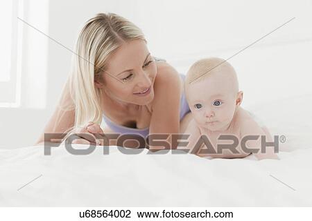 Stock Image - Mother and baby laying on bed. Fotosearch
