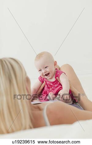 Mother and baby sitting on bed View Large Photo Image Stock Photography - Mother and baby sitting on bed. Fotosearch