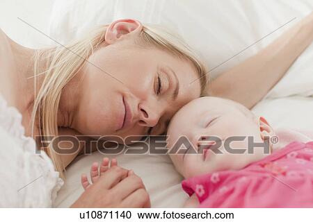 Stock Image - Mother and baby sleeping on bed. Fotosearch