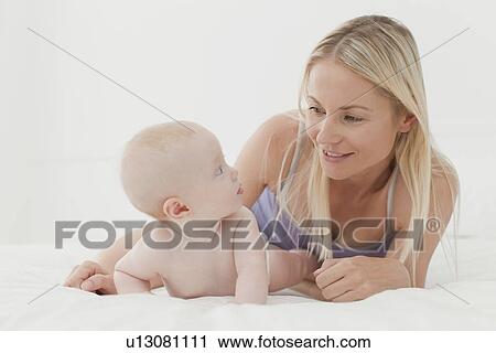 Mother and baby smiling on bed View Large Photo Image Stock Image - Mother and baby smiling on bed. Fotosearch