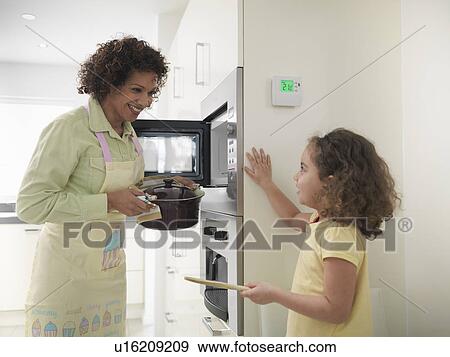 Stock Photo - Mother and daughter cooking together. Fotosearch