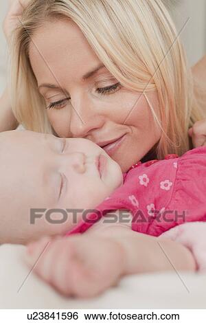 Mother kissing babys cheek on bed View Large Photo Image Stock Photograph - Mother kissing babys cheek on bed. Fotosearch