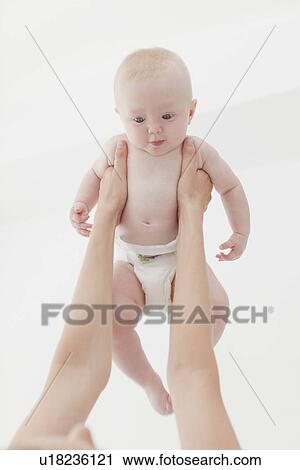 Stock Image - Mother lifting baby in air. Fotosearch