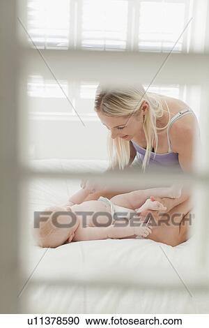 Mother playing with baby on bed View Large Photo Image Stock Image - Mother playing with baby on bed. Fotosearch