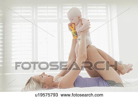 Mother playing with baby on bed View Large Photo Image Stock Image - Mother playing with baby on bed. Fotosearch