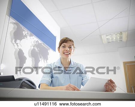 Stock Photograph - Nurse smiling at desk. Fotosearch