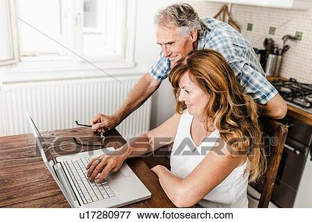 Older couple using laptop in kitchen View Large Photo Image Stock Photo - Older couple using laptop in kitchen. Fotosearch