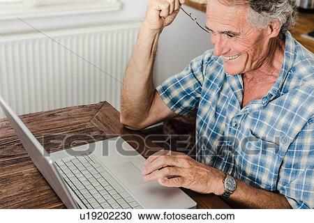 Older man using laptop in kitchen View Large Photo Image Stock Image - Older man using laptop in kitchen. Fotosearch