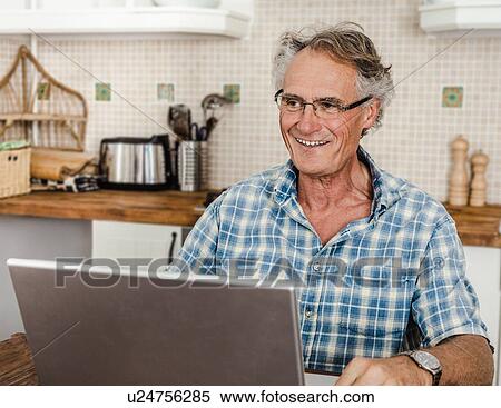 Older man using laptop in kitchen View Large Photo Image Stock Photography - Older man using laptop in kitchen. Fotosearch