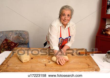 Stock Photo - Older woman kneading dough on board. Fotosearch
