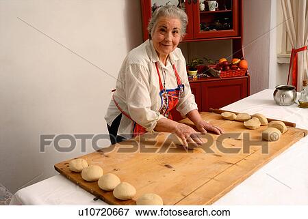 Older woman rolling dough on board View Large Photo Image Stock Photo - Older woman rolling dough on board. Fotosearch