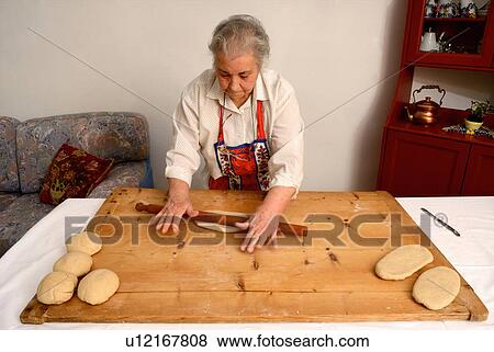 Older woman rolling dough on board View Large Photo Image Stock Photo - Older woman rolling dough on board. Fotosearch