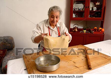 Stock Photo - Older woman stretching sheet of dough. Fotosearch