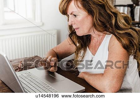 Older woman using laptop in kitchen View Large Photo Image Stock Photograph - Older woman using laptop in kitchen. Fotosearch