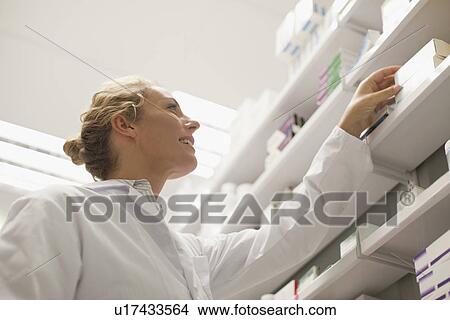 Pharmacist browsing medicines on shelf View Large Photo Image Picture - Pharmacist browsing medicines on shelf. Fotosearch