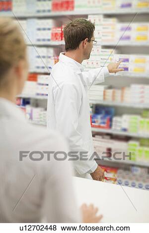 Stock Photo - Pharmacist browsing medicines on shelf. Fotosearch