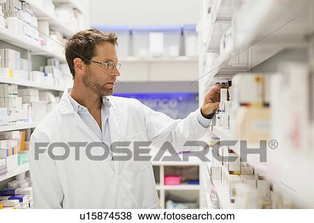 Pharmacist browsing medicines on shelf View Large Photo Image Stock Photo - Pharmacist browsing medicines on shelf. Fotosearch