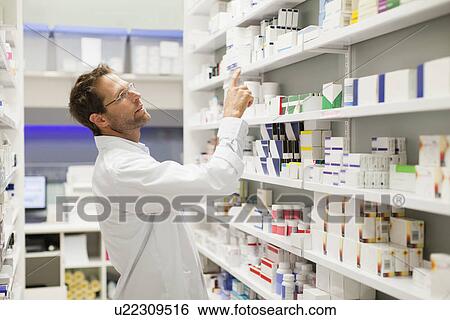 Pharmacist browsing medicines on shelf View Large Photo Image Stock Photograph - Pharmacist browsing medicines on shelf. Fotosearch