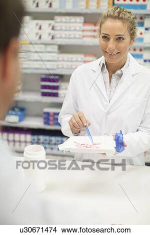 Pharmacist counting pills at counter View Large Photo Image Picture - Pharmacist counting pills at counter. Fotosearch