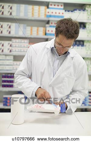 Pharmacist counting pills at counter View Large Photo Image Stock Photograph - Pharmacist counting pills at counter. Fotosearch