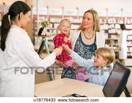 Pharmacist giving boy lollipop in store View Large Photo Image Stock Image - Pharmacist giving boy lollipop in store. Fotosearch