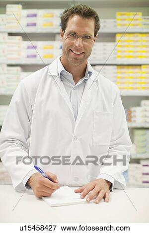 Pharmacist making notes at counter View Large Photo Image Stock Photo - Pharmacist making notes at counter. Fotosearch