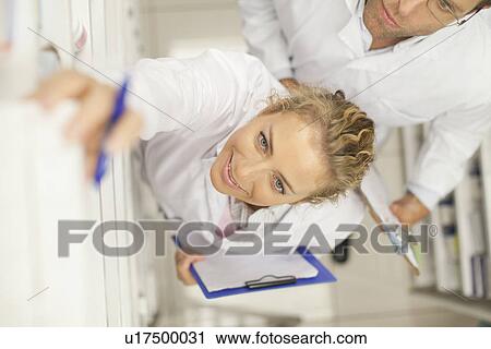 Stock Image - Pharmacist taking medicine on shelf. Fotosearch