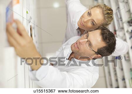 Stock Photo - Pharmacist taking medicine on shelf. Fotosearch