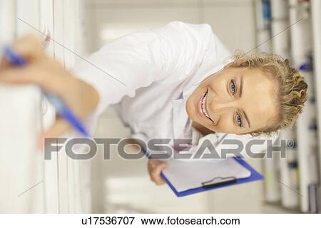Stock Photo - Pharmacist taking medicine on shelf. Fotosearch